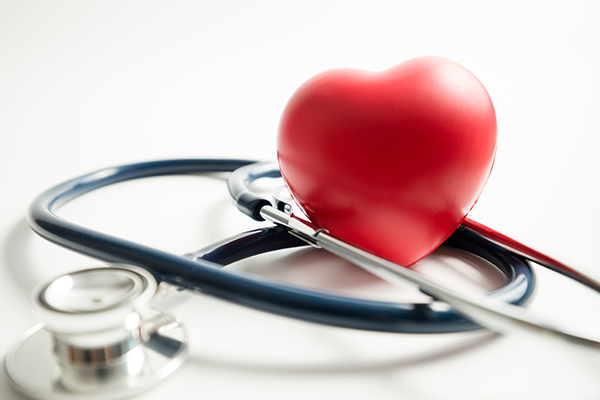 Black stethoscope with red heart toy on table