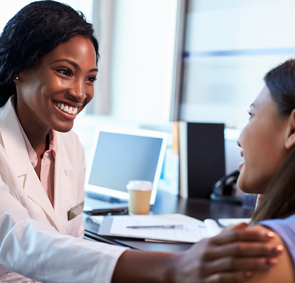 Female doctor placing hand on female patient arm while smiling