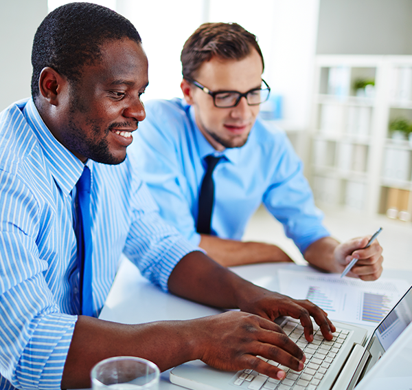 Two businessmen looking at computer and report wearing shirt and ties