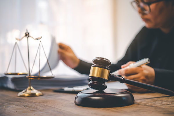 woman reading legal documents at a table with gavel and legal scales