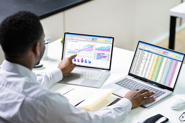 man working on two laptops