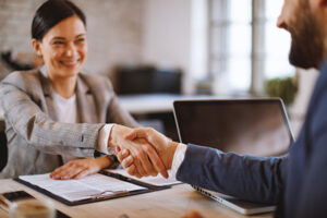 Man and woman shaking hands over a table