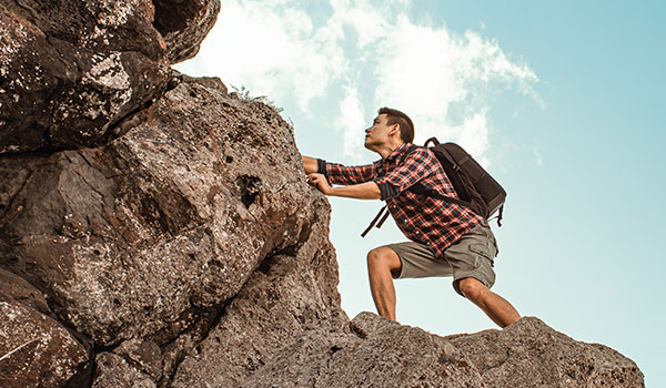 Person climbing rock with backpack