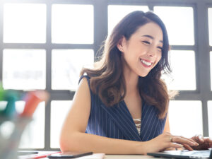 women smiling sitting at desk on computer